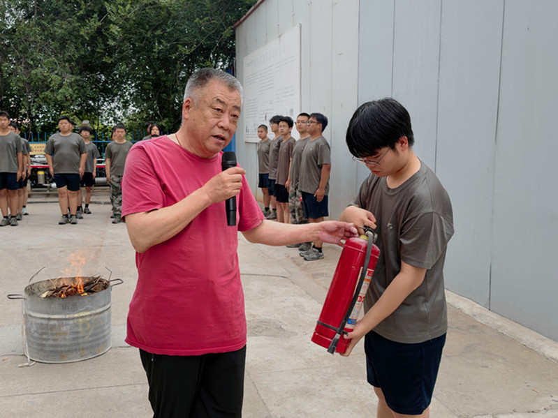 后勤安保处干事魏孔宇现场演示干粉灭火器 “提、拔、握、压” 操作方法